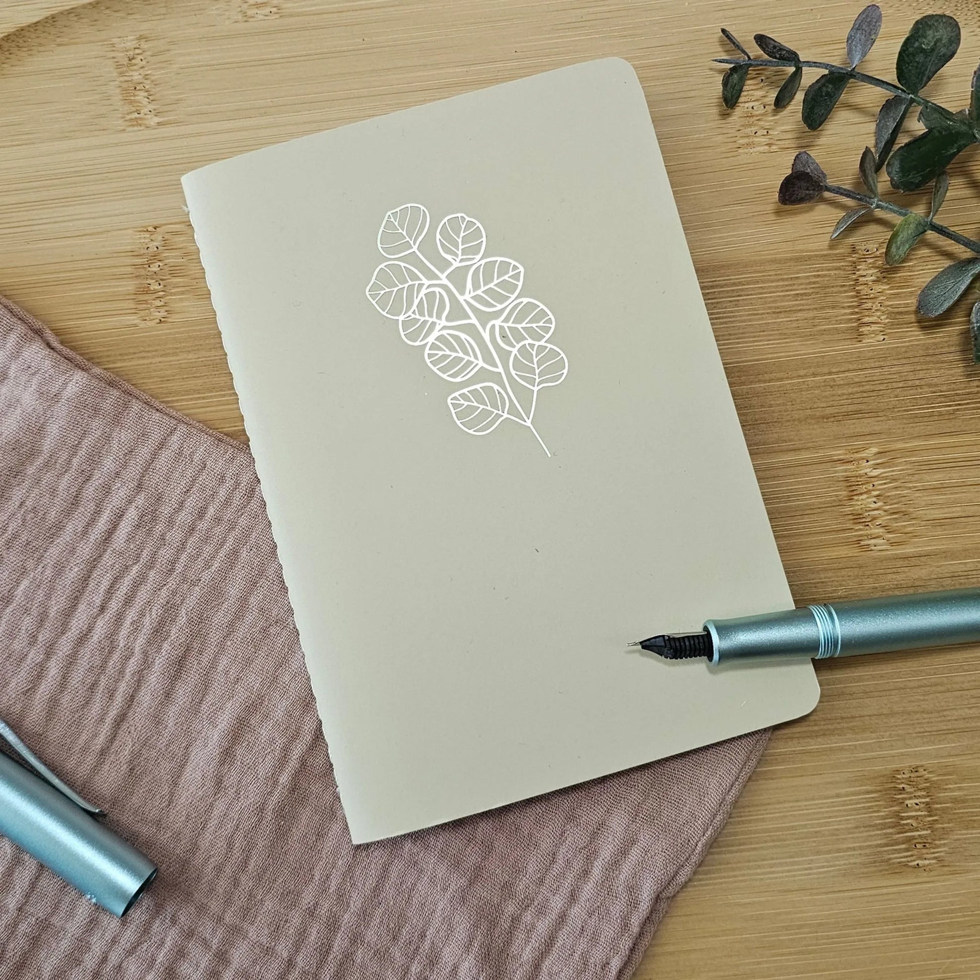 Artchemira A6 pocket journal with gold  foil botanical cover design and blue pen on bamboo plate
