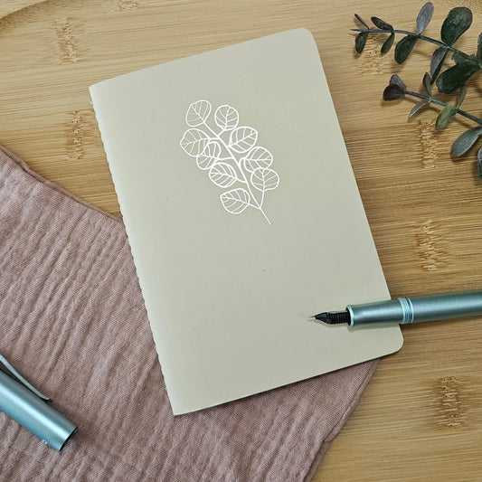 Artchemira A6 pocket journal with gold  foil botanical cover design and blue pen on bamboo plate