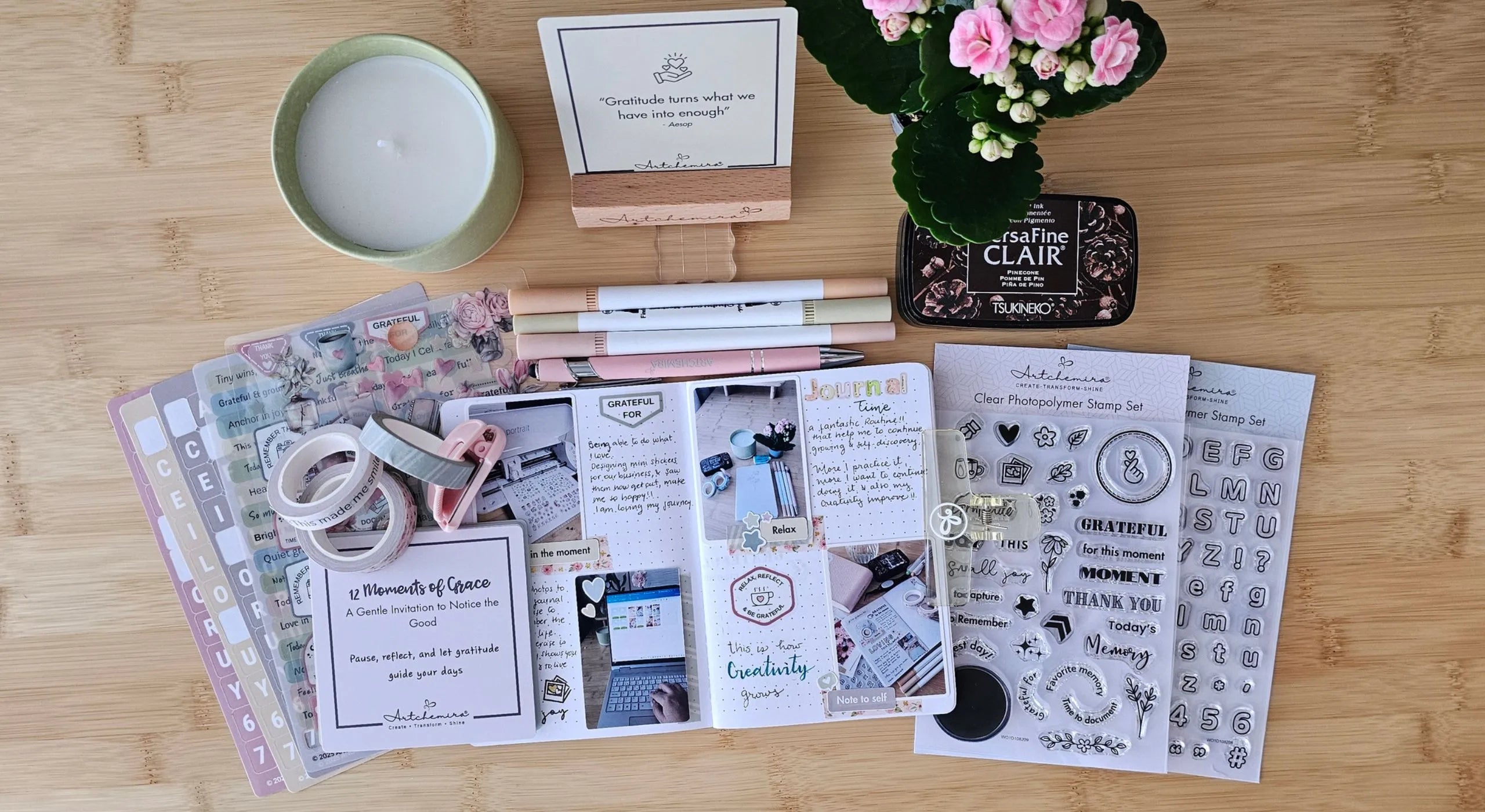 Artchemira stationery items including a candle, stationery set, and small plant on a wooden surface.