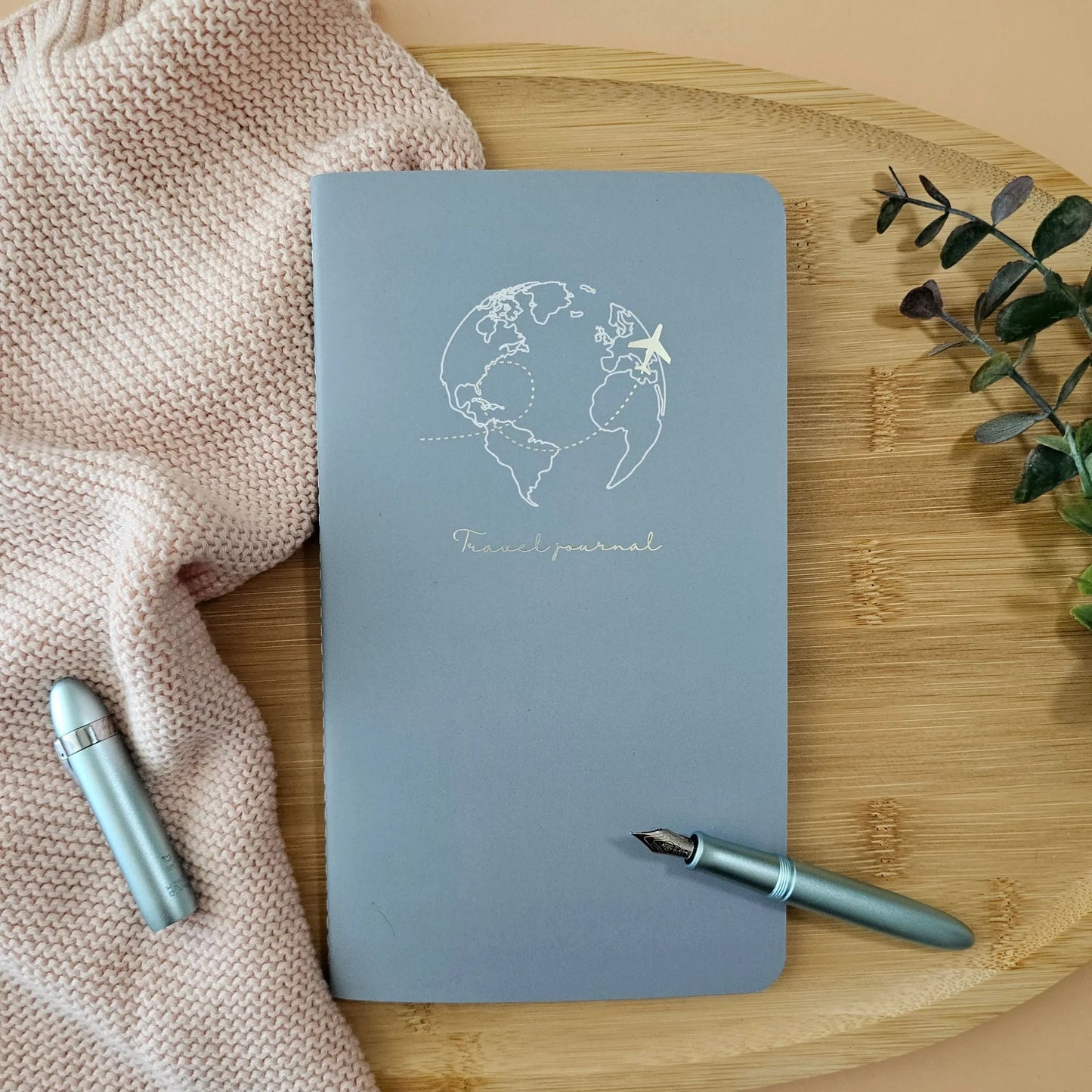 Artchemira large travel journal with champagne gold globe and plane foil cover, on bamboo surface
